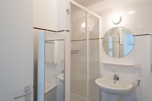 Baño blanco con lavabo y espejo en Hello Zeeland - Appartement Port Scaldis 19-042, en Breskens