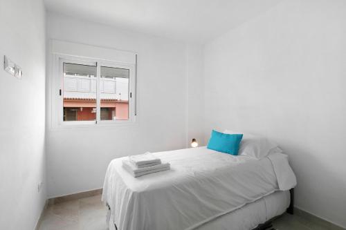 Dormitorio blanco con cama con almohada azul en Buganvilla 0-1, en Candelaria