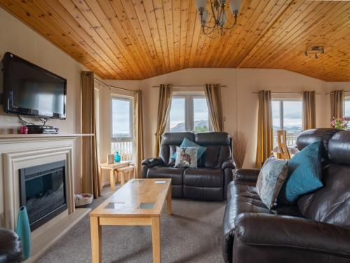 - un salon avec des canapés en cuir et une cheminée dans l'établissement Chalet Loch Leven Lodge 4 by Interhome, à Kinross