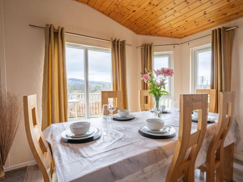 een eetkamer met een tafel, stoelen en ramen bij Chalet Loch Leven Lodge 4 by Interhome in Kinross