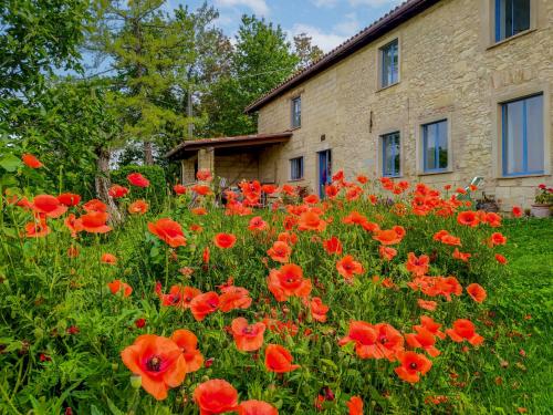 um campo de flores vermelhas em frente a um edifício em Holiday Home Cascina ConVista by Interhome em Grazzano Badoglio