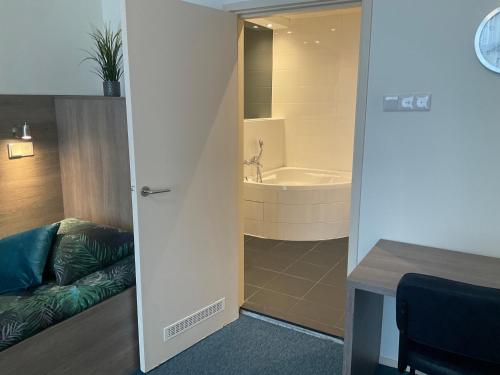 a bathroom with a tub and a couch in a room at Hotel Poseidon in Scheveningen