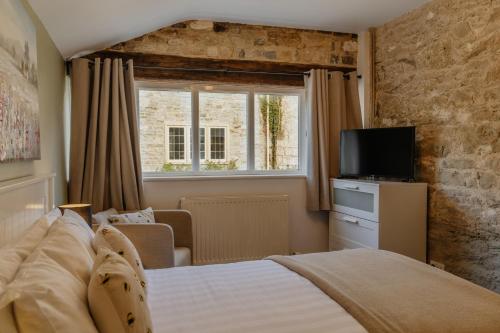 een slaapkamer met een bed, een raam en een televisie bij Little England Retreats - Cottage, Yurt and Shepherd Huts in Othery