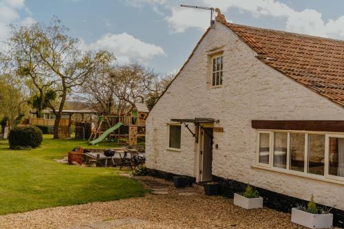 een huisje met een speeltuin op de achtergrond bij Little England Retreats - Cottage, Yurt and Shepherd Huts in Othery