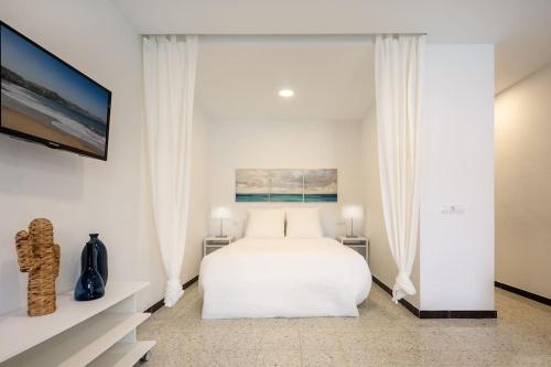 una camera da letto bianca con un letto e una TV di Puccini Oasis - Sole e amore a Las Palmas de Gran Canaria