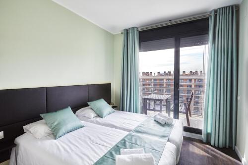 バルセロナにあるザ ロンリー チムニー アパートメントのベッドルーム1室(ベッド2台、大きな窓付)