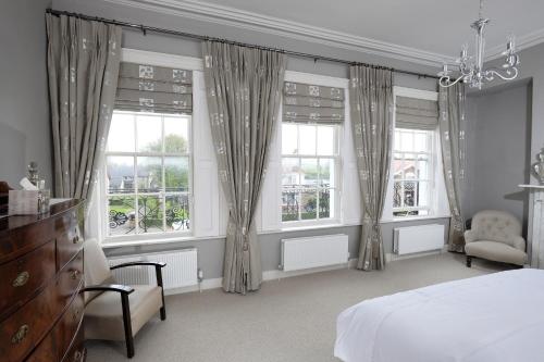 a bedroom with windows and a bed and a chair at Willoughby Place in Enniskillen