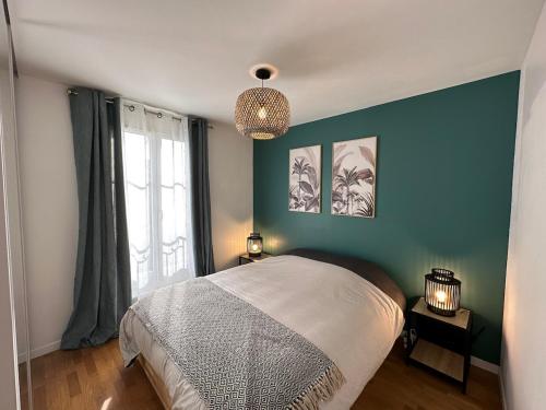 een slaapkamer met een bed en een blauwe muur bij L'escale du Trianon in Le Plessis-Robinson