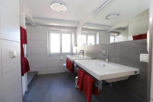ein Badezimmer mit zwei Waschbecken und roten Handtüchern in der Unterkunft KAISERS das kleine Stadthotel in Sonthofen
