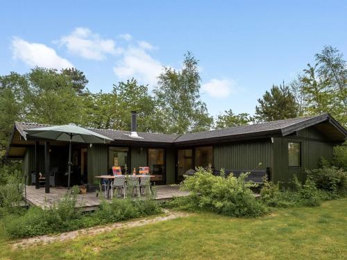 una casa verde con mesa y sombrilla en Holiday Home Lasse - 1-5km from the sea in Sealand by Interhome en Græsted