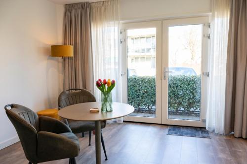 uma sala de estar com uma mesa com flores em B&B Witvliet, kamers en studio met heerlijk ontbijt ! em Zoutelande