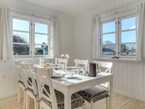 een witte eetkamer met een witte tafel en stoelen bij Holiday Home Ghita - 1-2km from the sea in Sealand by Interhome in Hornbæk