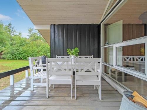 um alpendre com cadeiras brancas e uma mesa com uma planta em Holiday Home Fasti - 300m from the sea in Sealand by Interhome em Gilleleje