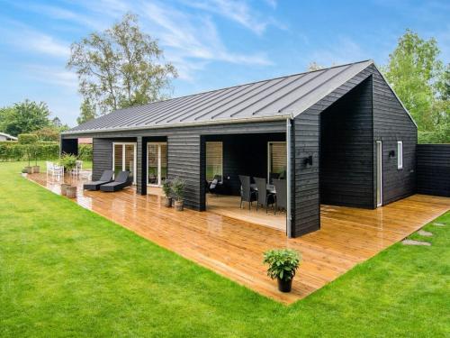 a black house with a wooden deck in a yard at Holiday Home Dorthie - 800m from the sea by Interhome in Hornbæk