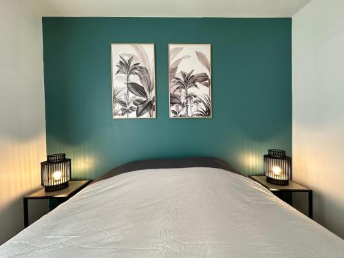 a bedroom with two lamps and a bed with three pictures on the wall at L'escale du Trianon in Le Plessis-Robinson
