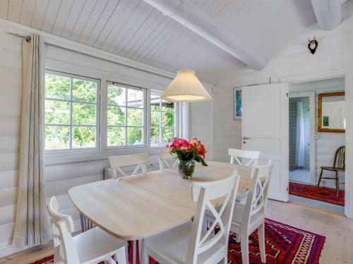 uma sala de jantar com uma mesa e cadeiras brancas em Holiday Home Ottil - 1km from the sea in Sealand by Interhome em Tisvildeleje