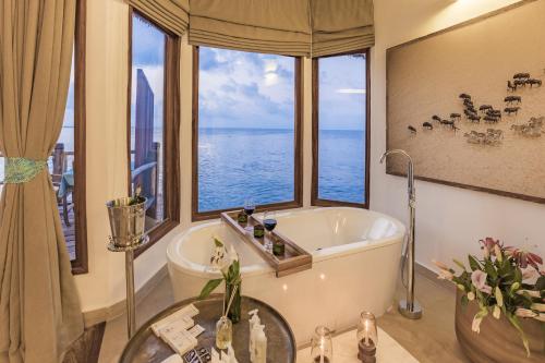 a bathroom with a tub and a large window at Konokono Beach Resort and Isaraya Luxury Overwater Villas in Michamvi