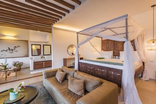 ein Wohnzimmer mit einem Bett und einem Sofa in der Unterkunft Konokono Beach Resort and Isaraya Luxury Overwater Villas in Michamvi