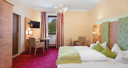 a hotel room with a large bed and a table at Hotel Liebl in Plattling
