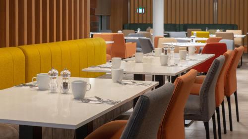 a dining room with tables and chairs at Holiday Inn Berlin Airport - Conference Centre by IHG in Schönefeld