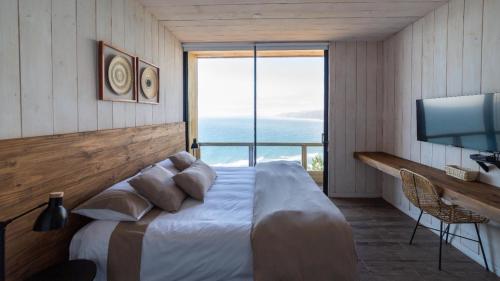 a bedroom with a large bed with a large window at Hotel Puerto Viejo Llico in Llico