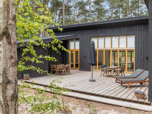 a black house with a wooden deck at Holiday Home Nuka - 800m from the sea in Bornholm by Interhome in Vester Sømarken
