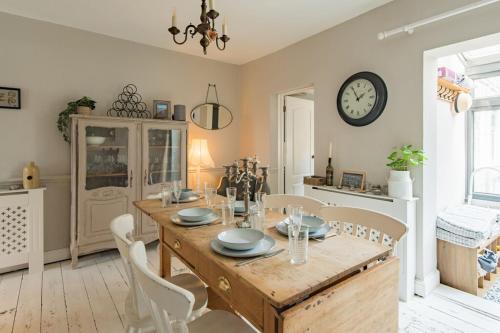 a dining room with a table and chairs and a clock at The House in Deal in Deal