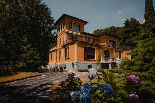 une grande maison orange avec des fleurs devant elle dans l'établissement Villa Mimosa au Lac - Estella Hotels Italia, à Toscolano Maderno