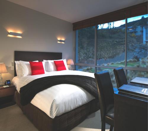 a bedroom with a large bed and a large window at Swiss-Belsuites Pounamu Queenstown in Queenstown