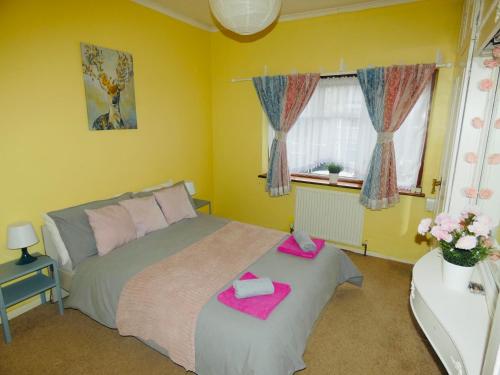 um quarto com uma cama com toalhas cor-de-rosa em SPACIOUS 3 BED HOUSE WITH PARKING & GOOD TRANSPORT em South Norwood