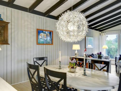 ein Esszimmer mit einem Tisch und einem Kronleuchter in der Unterkunft Holiday Home Claudette - 1km from the sea in Sealand by Interhome in Hornbæk