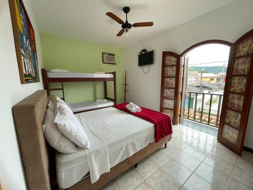 a bedroom with a bed with a fan and a balcony at Pousada Alecrim Dourado in Paraty