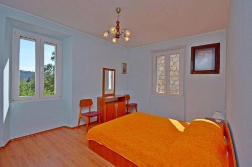 a bedroom with a bed and a desk and two windows at House Marija in Lastovo