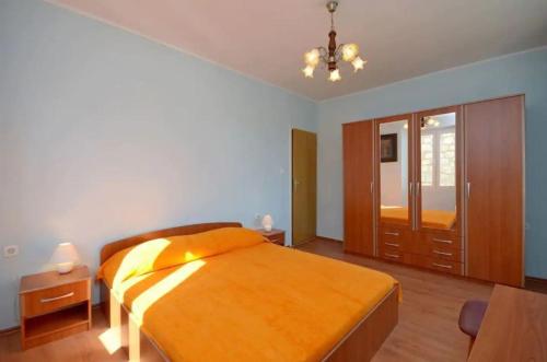 a bedroom with a large bed with an orange blanket at House Marija in Lastovo