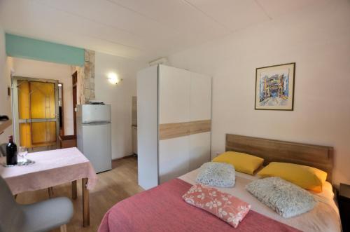 a bedroom with a bed and a table and a refrigerator at Apartments Maja in Štinjan