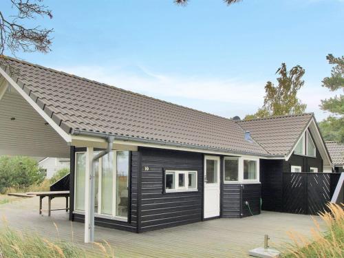 a black house with a deck in front of it at Holiday Home Ansgar - all inclusive - 150m from the sea in Bornholm by Interhome in Vester Sømarken