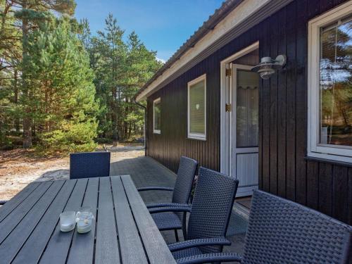 Une table et des chaises en bois sont disponibles sur la terrasse. dans l'établissement Holiday Home Hildegerd - 500m from the sea in Bornholm by Interhome, à Vester Sømarken