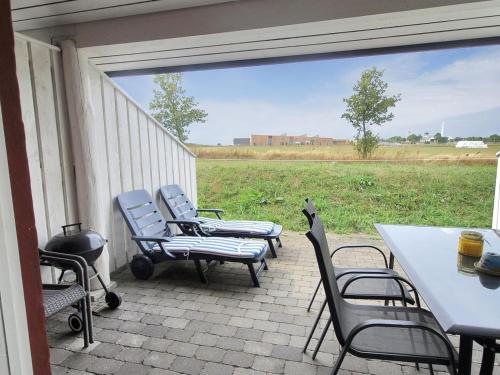 um grupo de cadeiras e mesas num pátio com um campo em Apartment Magnus - 6km from the sea in Bornholm by Interhome em Åkirkeby