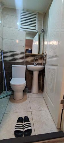 La salle de bains est pourvue de toilettes, d'un lavabo et d'une paire de chaussons. dans l'établissement Private Room in Istanbul #65, à Istanbul