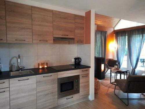 a kitchen with wooden cabinets and a living room at Secret Wellness Droombos in Holten