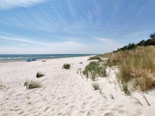 a sandy beach with grass and the ocean at Holiday Home Michel - 300m from the sea in Bornholm by Interhome in Vester Sømarken
