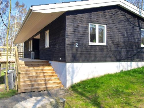 a small black house with a staircase and a window at Holiday Home Lätizia - 300m from the sea by Interhome in Svaneke