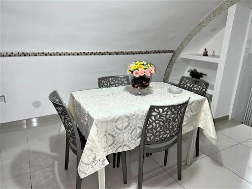 une table avec des chaises et un vase de fleurs. dans l'établissement Scalinatella, à Castellammare di Stabia