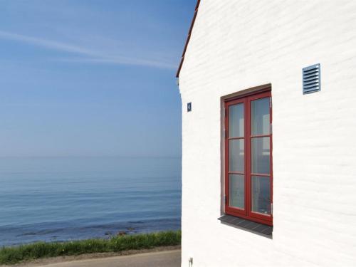 a white building with a red window next to the ocean at Holiday Home Uschi - 15m from the sea by Interhome in Hasle