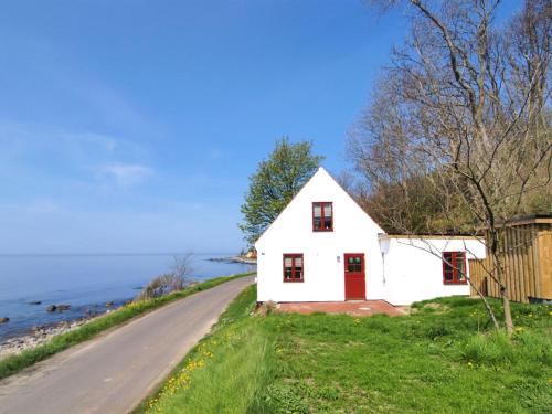a white house with red doors on the side of a road at Holiday Home Uschi - 15m from the sea by Interhome in Hasle