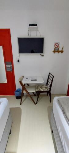 a room with a table and a chair and a tv at Hotel Casa Bonita in Campo Grande