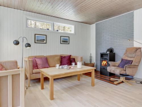 a living room with a couch and a table and a fireplace at Holiday Home Mikkelina - 700m from the sea in Bornholm by Interhome in Vester Sømarken