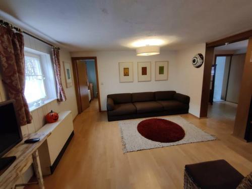 a living room with a black couch and a red rug at Gemütliche Bauernkate für 4 mit Kachelofen in Lelkendorf