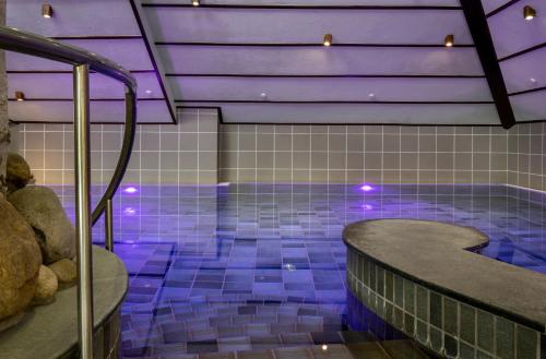 a swimming pool with purple lighting in a building at Köhlers Forsthaus Wellness & Genuss Hotel in Aurich