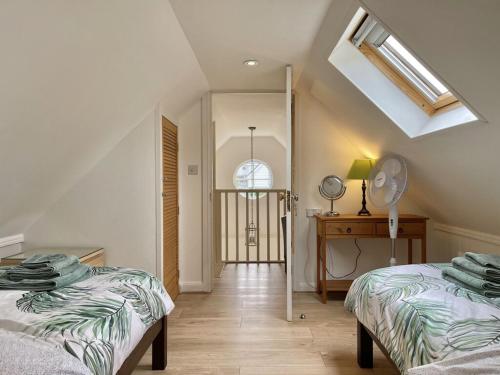 a attic room with two beds and a window at Sea Rose Cottage in Kingsdown